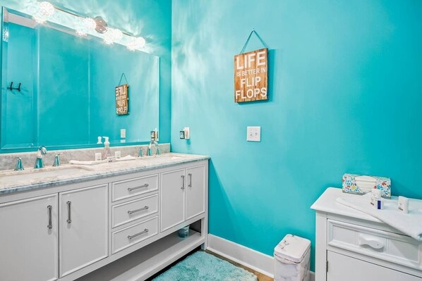 A bathroom with a turquoise wall, a double sink vanity, and a mirror with lights. - Windy Lane Leisure Retreat (Pawleys Island)
