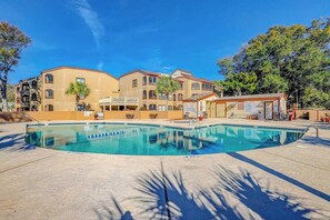 A swimming pool with a clear blue water surface, surrounded by a building with multiple balconies and a covered area. - Dunes Pointe Unit B-11 (Myrtle Beach)