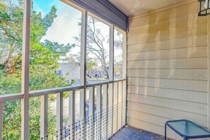 A covered porch with a view of a residential area, a metal railing, and a small table. - Toby Ct Unit A202 Condo (North Myrtle Beach)