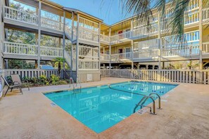 A multi-level hotel with a swimming pool, balconies, and outdoor seating. - Toby Ct Unit A202 Condo (North Myrtle Beach)