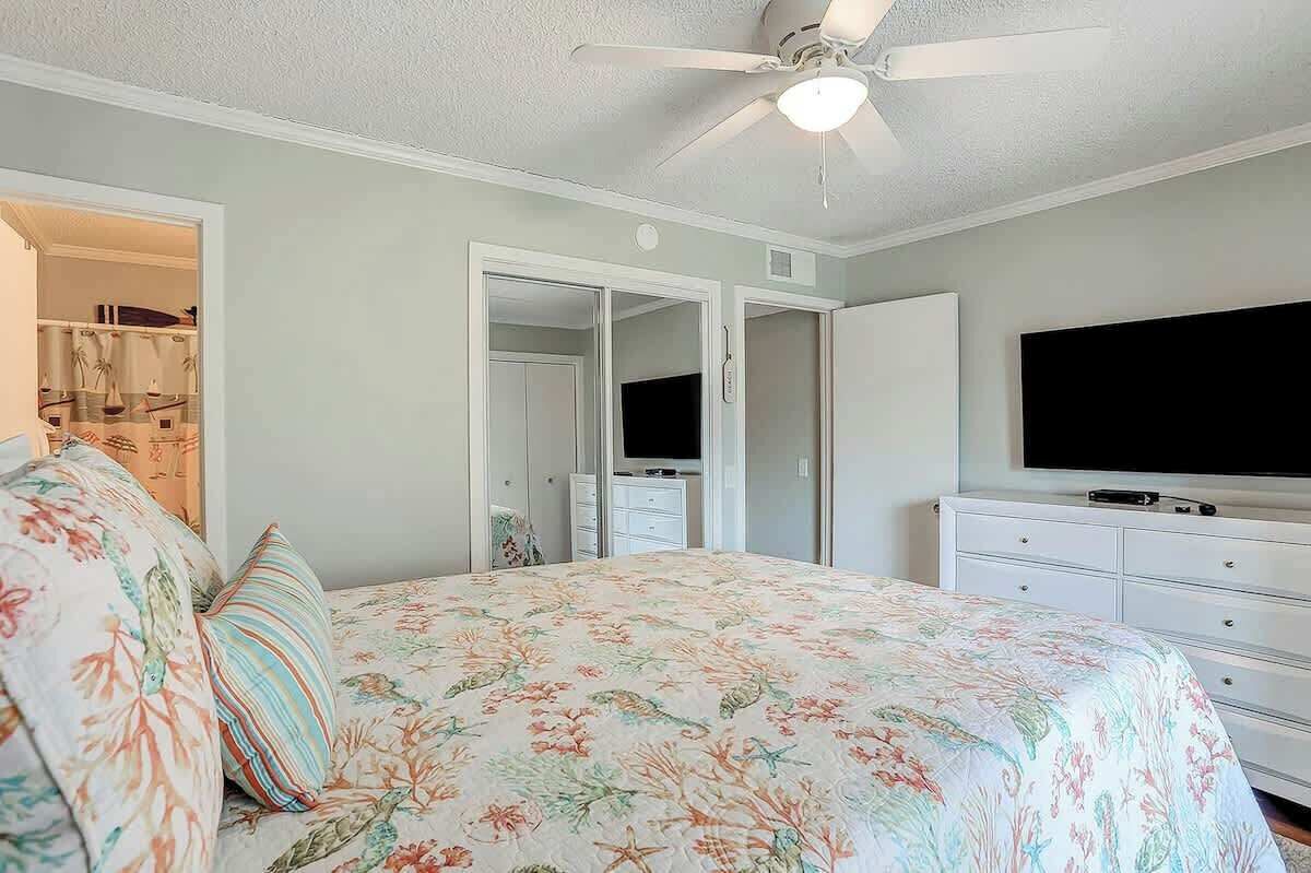 Ein Schlafzimmer mit Bett, Fernseher, Deckenventilator und Kleiderschrank.