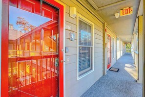 A corridor with a red door, a sign with the number '202A', and an 'EXIT' sign above. - Toby Ct Unit A202 Condo (North Myrtle Beach)