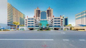 A modern hotel with a central glass atrium, multiple floors, and a parking area in front. - Beach Blessing Retreat (Myrtle Beach)