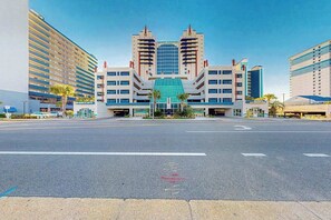 Ein modernes Hotel mit einem zentralen Glasatrium, mehreren Etagen und einem Parkplatz davor.