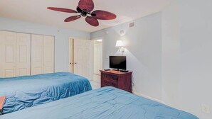 A bedroom with two beds, a ceiling fan, a TV on a wooden dresser, and white doors. - Beach Blessing Retreat (Myrtle Beach)