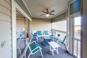 A covered porch with a ceiling fan, a small table, and several chairs. - Tidewater Retreat Condo (North Myrtle Beach)