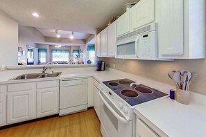 A modern kitchen with white cabinetry, a built-in microwave, a stove, and a dishwasher. - Tidewater Retreat Condo (North Myrtle Beach)