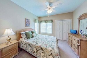 A bedroom with a bed, a nightstand, a dresser, a ceiling fan, and a television. - Tidewater Retreat Condo (North Myrtle Beach)
