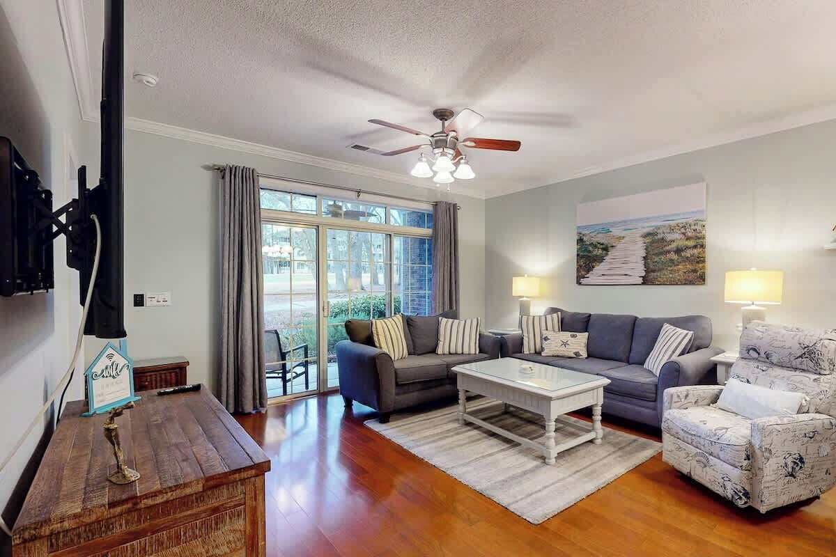 A living room with a ceiling fan, two couches, a coffee table, and a large window with curtains.