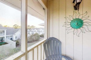 Ein Balkon mit Blick auf Häuser, einem Stuhl und einer Sonnendekoration.