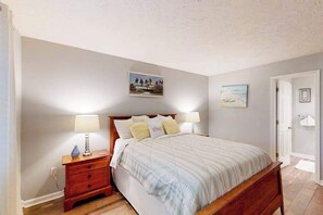 Ein Schlafzimmer mit Bett, Nachttischen und Wandbildern.