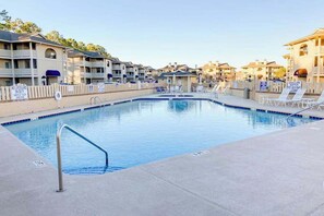 A swimming pool with a lifeguard stand, lounge chairs, and a fence. - Pinehurst Unit X-7 Condo (Little River)