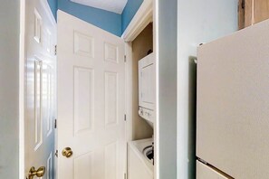 A room with a white door, a washing machine, and a refrigerator. - Pinehurst Unit X-7 Condo (Little River)