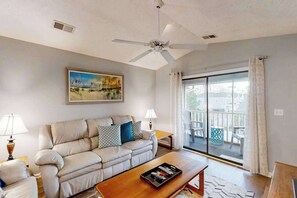 A living room with a sofa, coffee table, and a painting on the wall. - Pinehurst Unit X-7 Condo (Little River)