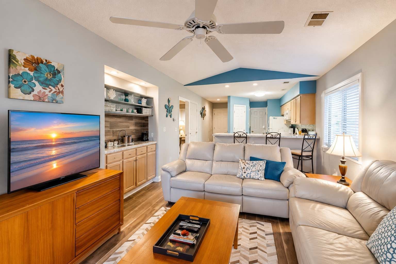 A living room with a sofa, coffee table, TV, and a ceiling fan.