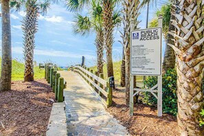 A pathway leading to a beach with a sign indicating public beach access and regulations. - Waipani Unit A-18 Condo (North Myrtle Beach)