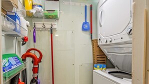 Ett tvättrum med tvättmaskin, mopp och rengöringsmedel.