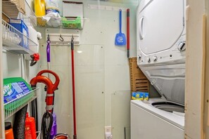 Ein Waschraum mit Waschmaschine, einem Mopp und Reinigungsmitteln.