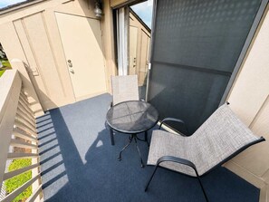A balcony with a round table and two chairs, a sliding glass door, and a view of a building. - Shipwatch Pointe II L-302 (Myrtle Beach)
