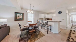 A modern kitchen with white cabinets, a central island, and bar stools. - 1033 World Tour Unit 306 (Myrtle Beach)