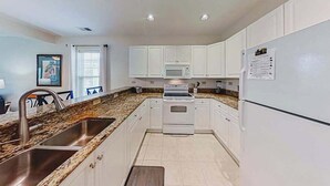 A modern kitchen with white cabinets, a stainless steel sink, and a built-in oven. - 1033 World Tour Unit 306 (Myrtle Beach)