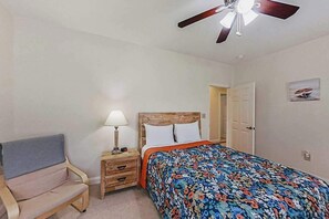 A bedroom with a bed, a nightstand, a chair, a ceiling fan, and a door. - 1033 World Tour Unit 306 (Myrtle Beach)