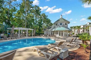 A pool area with lounge chairs and a gazebo.