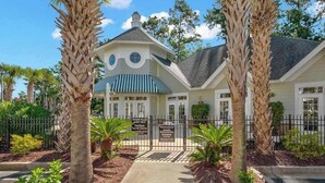A two-story building with a gated entrance, palm trees, and a sign indicating it is a private villa. - 1033 World Tour Unit 306 (Myrtle Beach)
