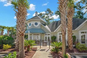 A two-story building with a gated entrance, palm trees, and a sign indicating it is a private villa.