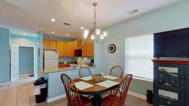 A dining area with a round table, chairs, and a chandelier. - Homey Beach Hideaway C (Myrtle Beach)