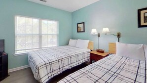 A room with two beds, a window, a nightstand, a lamp, and a framed picture on the wall. - Homey Beach Hideaway C (Myrtle Beach)