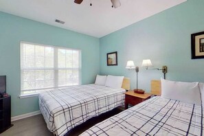 A room with two beds, a window, a nightstand, a lamp, and a framed picture on the wall. - Homey Beach Hideaway C (Myrtle Beach)