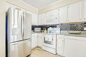 A modern kitchen with white cabinetry, stainless steel appliances, a microwave, toaster, and a dishwasher. - Hillside Unit 304 Condo (North Myrtle Beach)