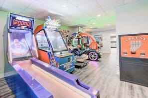 A room with arcade machines, including a baseball game and a racing game, and a Tokens advertisement on the wall. - Z-Beach Colony Unit 415 (Myrtle Beach)