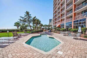 Uma área de piscina de hotel com espreguiçadeiras e um edifício com várias varandas.