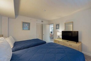 A hotel room with two beds, a television on a stand, and a door leading to a hallway. - Z-Beach Colony Unit 415 (Myrtle Beach)