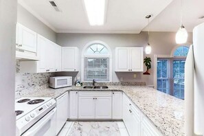 A kitchen with white cabinets, a microwave, a stove, and a sink. - Riverwalk Unit 301 Condo (Myrtle Beach)