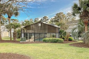 A modern building with a large glass facade, surrounded by a well-maintained lawn and various trees. - Riverwalk Unit 301 Condo (Myrtle Beach)
