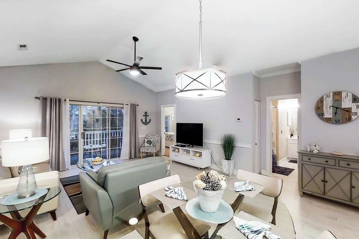 A modern living room with a sofa, television, dining table, and chairs.