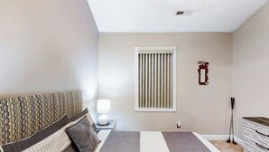 A bedroom with a bed, bedside table, lamp, window, and a dresser. - Riverwalk Unit 301 Condo (Myrtle Beach)