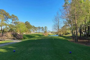 A golf course with a clear sky, trees, and a well-maintained green. - Riverwalk Unit 301 Condo (Myrtle Beach)
