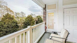 A balcony with a white railing, a door, and a chair. - Riverwalk Unit 301 Condo (Myrtle Beach)