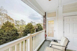 A balcony with a white railing, a door, and a chair. - Riverwalk Unit 301 Condo (Myrtle Beach)