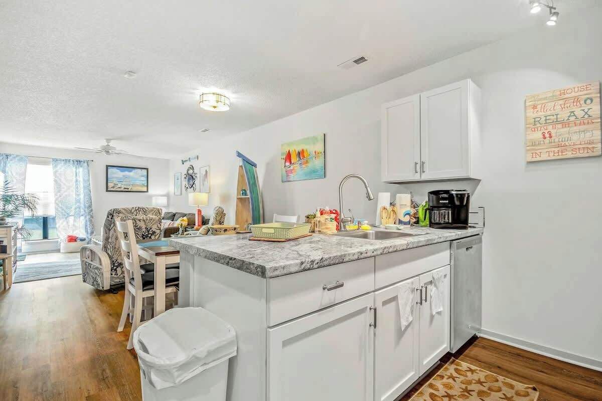 A kitchen with white cabinets, a marble countertop, and a coffee maker.