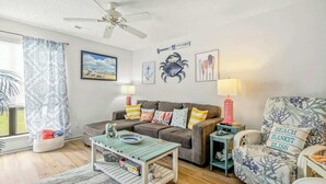Ein Wohnzimmer mit einer Couch, Sesseln, einem Couchtisch und einem Deckenventilator.