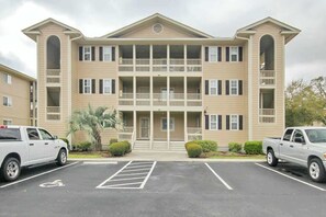 A multi-story hotel with a central entrance, balconies, and a parking lot with marked handicapped spaces. - Starkissed Beach Retreat (North Myrtle Beach)