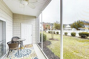 A covered porch with a door, two chairs, and a patterned rug. - Scotch Broom Unit E-104 (Little River)