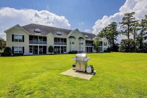 A two-story house with a large front lawn and a barbecue grill in the center. - Scotch Broom Unit E-104 (Little River)