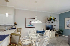 A dining area with white chairs, a white table, and a chandelier. - Scotch Broom Unit E-104 (Little River)