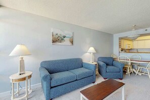 Ein Wohnzimmer mit einer Couch, zwei Sesseln, einem Couchtisch und einem Essbereich mit Tisch und Stühlen.